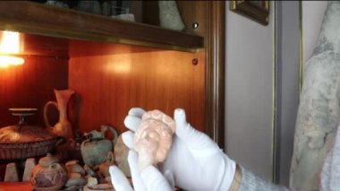 Nadir arkeolojik buluntular beyaz eldiven giyen kişi tarafından tutuluyor. Özel Müze, İtalya, Sicilya