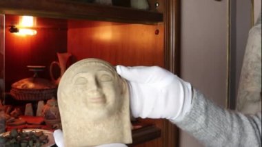Nadir arkeolojik buluntular beyaz eldiven giyen kişi tarafından tutuluyor. Özel Müze, İtalya, Sicilya