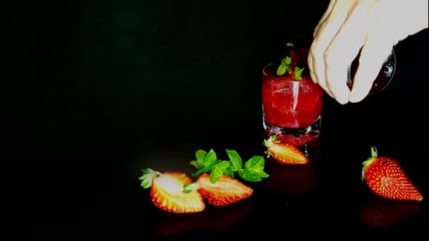 喝在黑色背景新鲜的红色鸡尾酒与冰块和薄荷叶 红色夏季浆果 美味的多汁饮料 — 图库视频影像