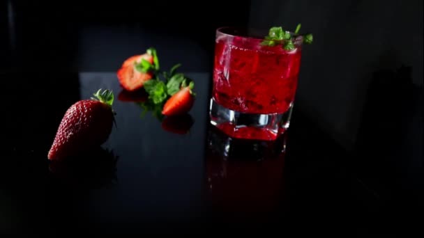 喝在黑色背景新鲜的红色鸡尾酒与冰块和薄荷叶 红色夏季浆果 美味的多汁饮料 — 图库视频影像