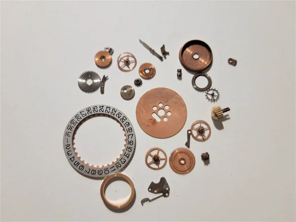 Assorted Clockwork spare part on white background with shadows.