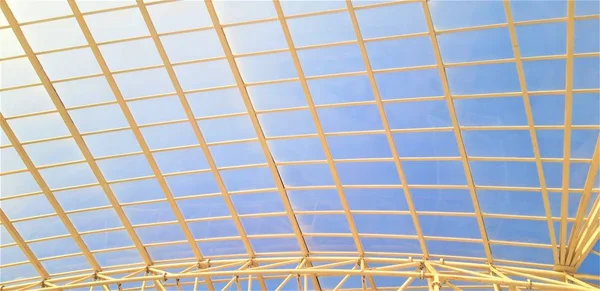 metal and glass greenhouse ceiling construction in blue sky