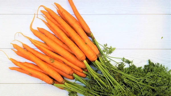 fresh homegrown carrots on white wooden surface