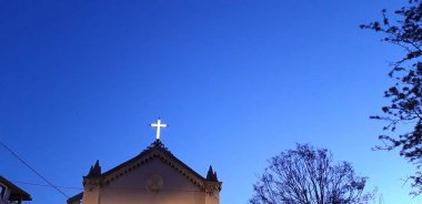 akşam gökyüzünde ışıklı haç ile kilise binası üst