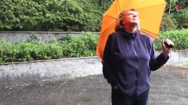 turuncu bir şemsiye ile yağmurda orta yaşlı kadın