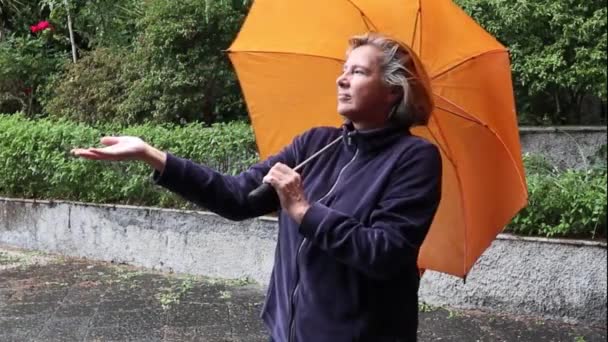 Μεσήλικες Γυναίκα Στη Βροχή Μια Πορτοκαλί Ομπρέλα — Αρχείο Βίντεο