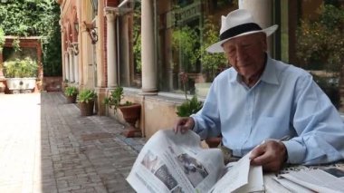 İhtiyar basını okuyor. parkta otururken gazete okuyan kıdemli adam