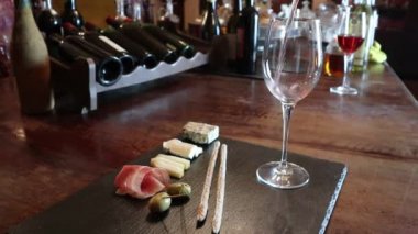 Şarap testi, kristal cam, kırmızı şarap, peynir, bar tezgahı arka planı. Bir bardak şarap ve peynir tabağı. Şarap testi.