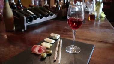 Şarap testi, kristal cam, kırmızı şarap, peynir, bar tezgahı arka planı. Bir bardak şarap ve peynir tabağı. Şarap testi.