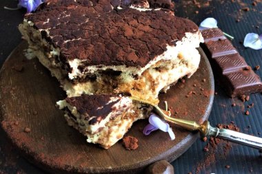 Çatal ve gcine ile ahşap bir tahta üzerinde lezzetli dilimlenmiş tiramiisu