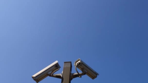 青空に対する2台の防犯カメラが監視スペースをコピーしています 背景として青空に対する2つの監視カメラ — ストック動画