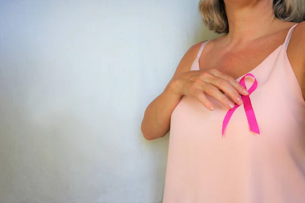 Woman wih pink ribbon on chest.  mature female  showing symbol r