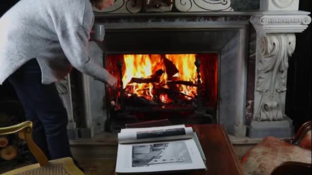 古董雕刻大理石壁炉 火和书桌上古老的雕刻大理石壁炉 妇女读一本书 — 图库视频影像