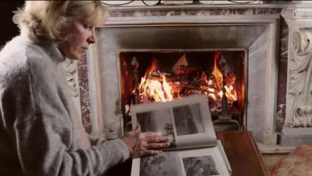アンティーク彫刻大理石の暖炉 火とテーブルの上の本古代彫刻大理石の暖炉 本を読む女性 — ストック動画