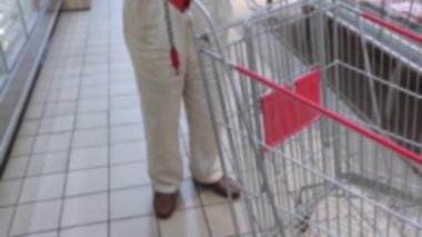 Yaşlı yaşlı yalnız adam alışveriş için bir süpermarkette araba ile geldi. bulanık arka plan. 