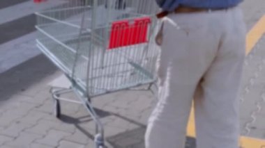 Yaşlı yaşlı yalnız adam alışveriş için bir süpermarkette araba ile geldi. bulanık arka plan. 