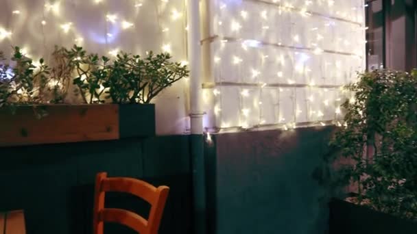 きらめくボケを飾る新年のライト 街のクリスマスと新年の花輪のきらめくライト 冬のクリスマスホリデーストリートのために美しく飾られた上を歩く歩行者のデフォーカスビュー — ストック動画