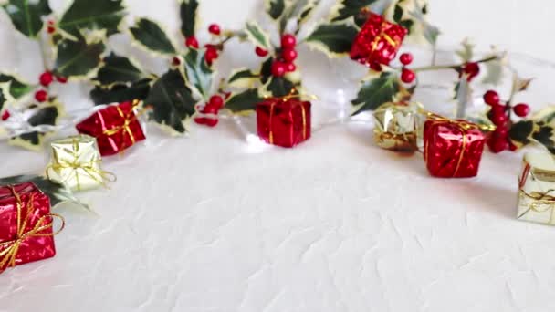 点滅する光の背景にクリスマスリースの装飾品の小枝ホリーと贈り物を作成します 象徴的なイメージ クリスマスの背景 スペースのコピー — ストック動画