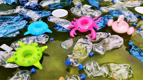 pollution of the environment. plastic bottles in water and inflatable toys. Inflatable pink flamingos, green turtle, blue fish, raspberry crayfish among plastic garbage