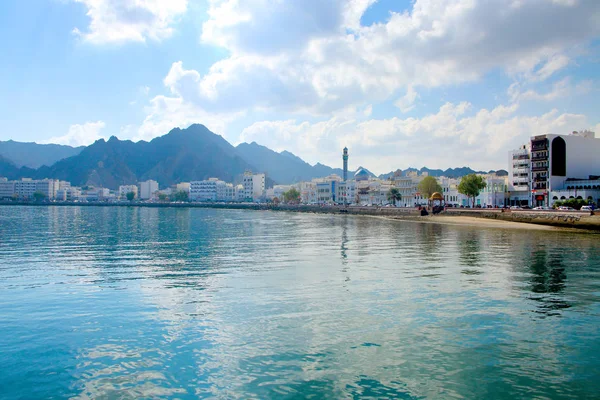 Waterkant van de stad Muscat, Oman, met gebouwen op de voorgrond & omgeven door bergen achter. — Stockfoto