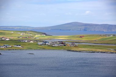 Arka planda, Shetland Adaları, İskoçya 'da köyleri ve adaları olan güzel bir manzara..