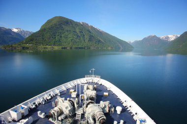 Norveç 'in batısındaki Sognefjord ya da Sognefjorden' de seyreden bir geminin önünde ya da önünde. Dağların fiyortlarında yansımaları olan güzel bir manzara.. 