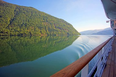 Norveç 'in batısındaki Sognefjord ya da Sognefjorden, Vestland bölgesinde seyir halindeki bir geminin güvertesi. Dağların fiyortlarında yansımaları olan güzel bir manzara.. 