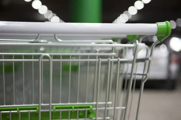 Many metal shopping carts on a parking lot near supermarket outdoors. Shopping concept. The image can be used as a background, there is room for text placement