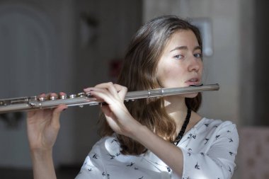 Genç güzel girlr yakın çekim tür portresi bir flüt üzerinde oynarken poz güzel bir kadın