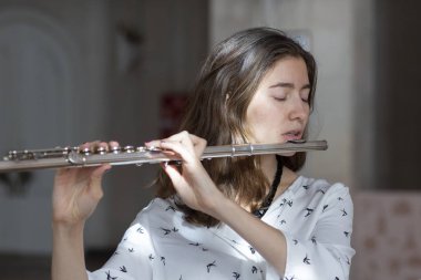 Genç güzel girlr yakın çekim tür portresi bir flüt üzerinde oynarken poz güzel bir kadın