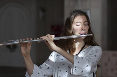 Genç güzel girlr yakın çekim tür portresi bir flüt üzerinde oynarken poz güzel bir kadın