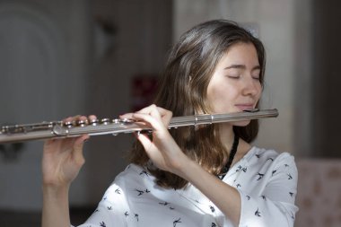 Genç güzel girlr yakın çekim tür portresi bir flüt üzerinde oynarken poz güzel bir kadın