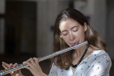 Genç güzel girlr yakın çekim tür portresi bir flüt üzerinde oynarken poz güzel bir kadın