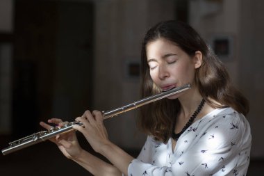 Genç güzel girlr yakın çekim tür portresi bir flüt üzerinde oynarken poz güzel bir kadın