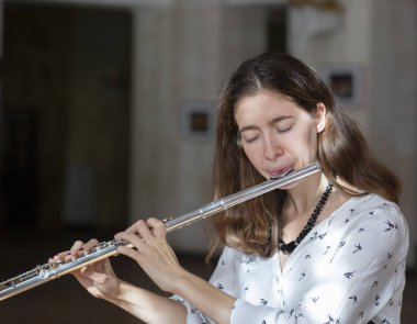 Genç güzel girlr yakın çekim tür portresi bir flüt üzerinde oynarken poz güzel bir kadın