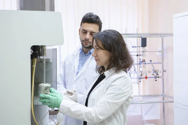 女性研究的科学家在一个大型的现代化实验室使用微管吸吮灌装试管 在背景科学家的工作 — 图库照片