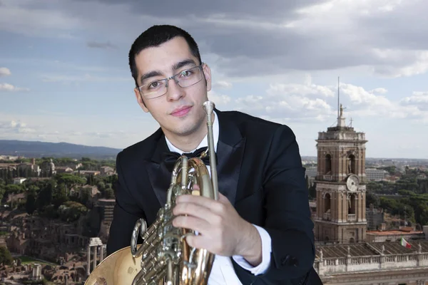 French horn player. Hornist playing brass orchestra music Portrait on the background of the city Close-up