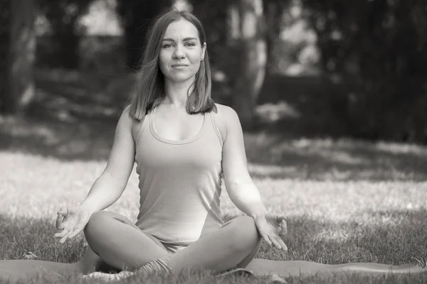 Pretty woman doing yoga exercises in the park Black and white image Portrait