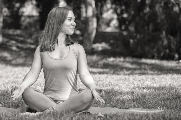 Pretty woman doing yoga exercises in the park Black and white image Portrait