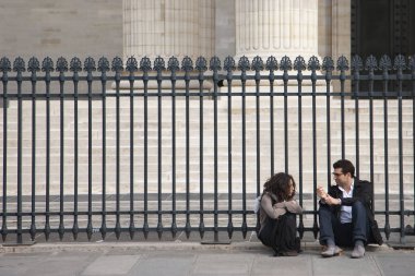 Paris, France - April 12, 2011: young woman and man sitting together near fenceGenre