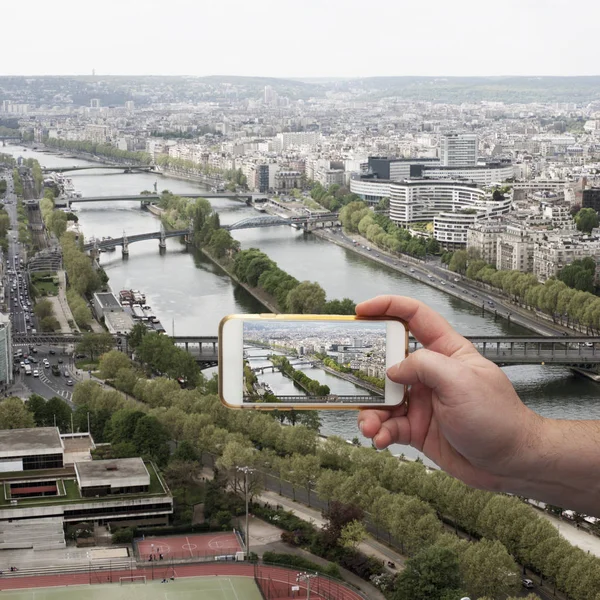 Scenic view of historical center Paris bridge and buildings of old town Hand with a smartphone, on the screen of which the urban landscape