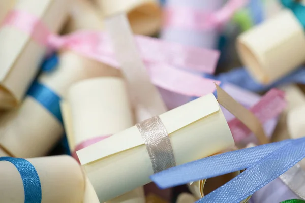 Pile of small paper scrolls White scrolls tied with blue and pink ribbon. Future prediction, advice or sign concept