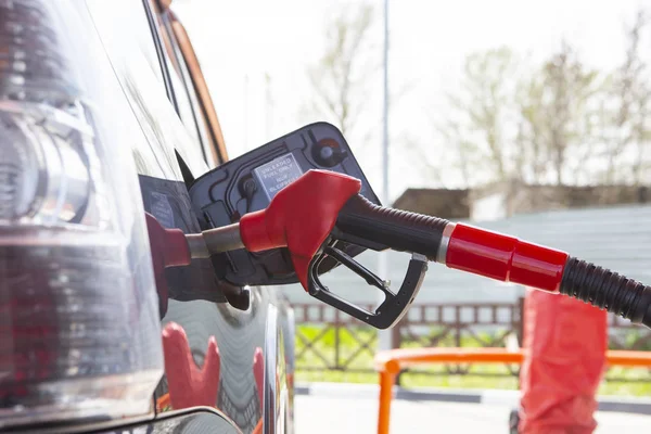 Llena el auto con combustible. El coche está lleno de gasolina en una gasolinera. Bomba de gasolinera. Hombre repostando gasolina con combustible en un coche, sosteniendo una boquilla. Profundidad de campo limitada. Imagen borrosa — Foto de Stock