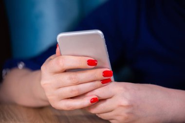 yakın çekim, kırmızı manikür ile kadın eller beyaz bir arka plan üzerinde bir akıllı telefon kullanın. Sınırlı alan derinliği