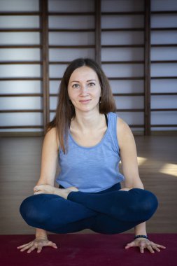 Güzel genç kadın loft iç çalışma, mavi paspas yoga egzersiz yapıyor, çapraz bacaklar ile kol dengesi egzersiz, Ölçek Duruş, Tolasana, Utpluthi Pose, tam uzunlukta