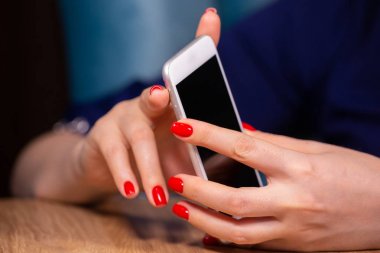 yakın çekim, kırmızı manikür ile kadın eller beyaz bir arka plan üzerinde bir akıllı telefon kullanın. Sınırlı alan derinliği
