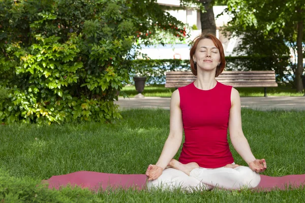 Mujer en una esterilla de yoga para relajarse al aire libre. — Foto de Stock