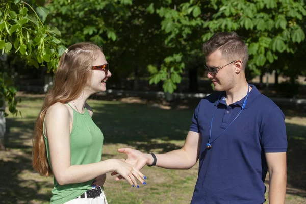 Bonita pareja abrazándose y coqueteando en un parque urbano sentada en un banco y mirando hacia otro lado — Foto de Stock