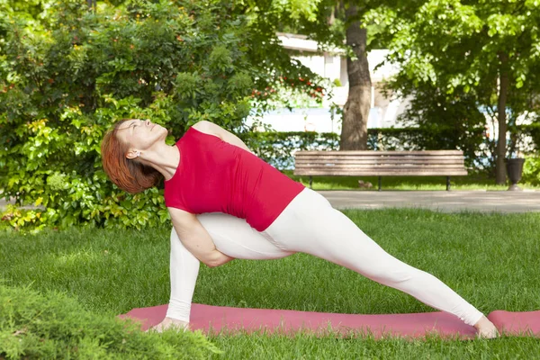 Lächelndes Mädchen im Park Übung auf der Yogamatte, hoher Ausfallschritt — Stockfoto