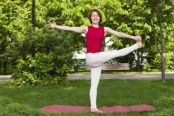 Lächelndes Mädchen im Park Übung auf der Yogamatte, hoher Ausfallschritt — Stockfoto